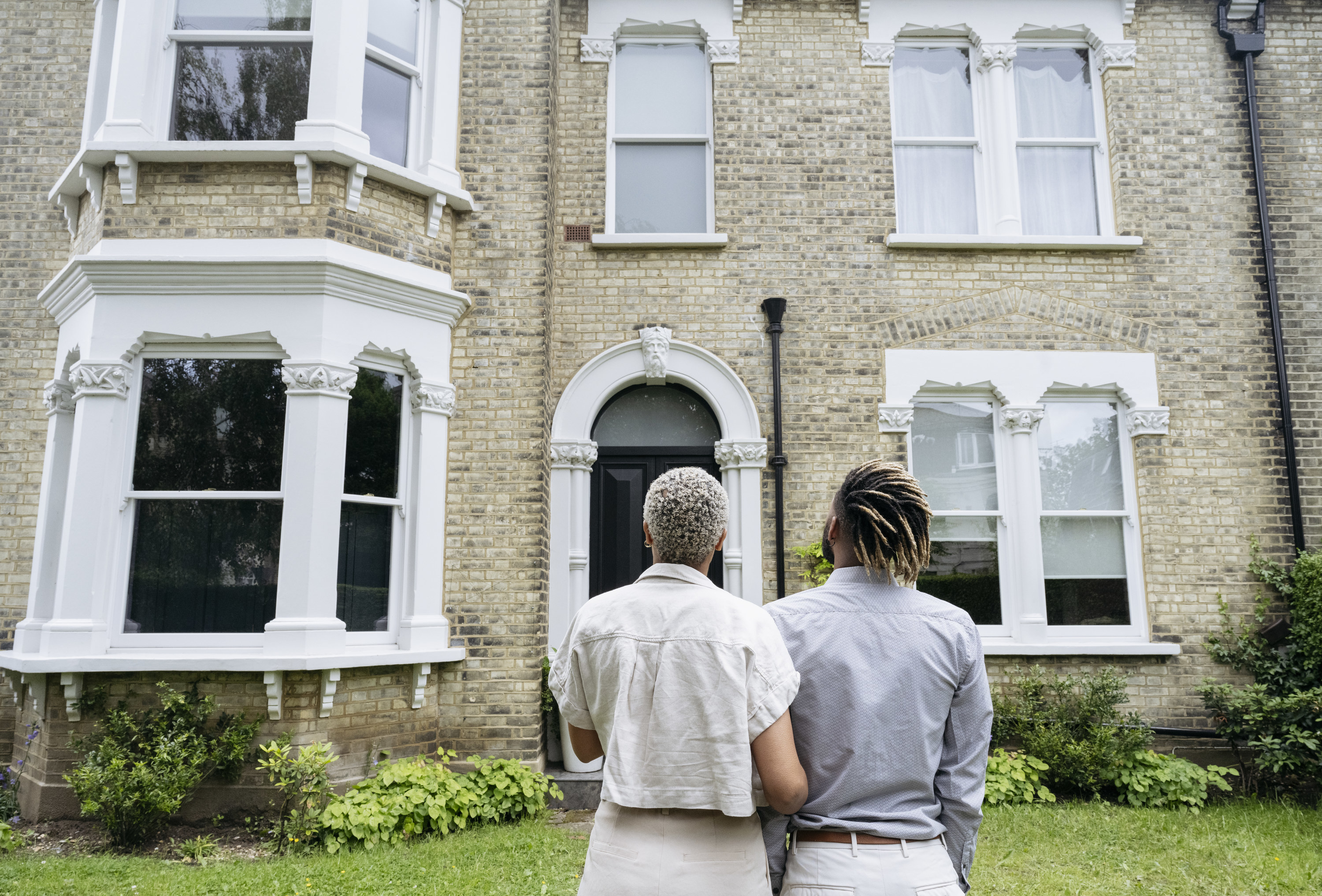 Two black people standing outside a home