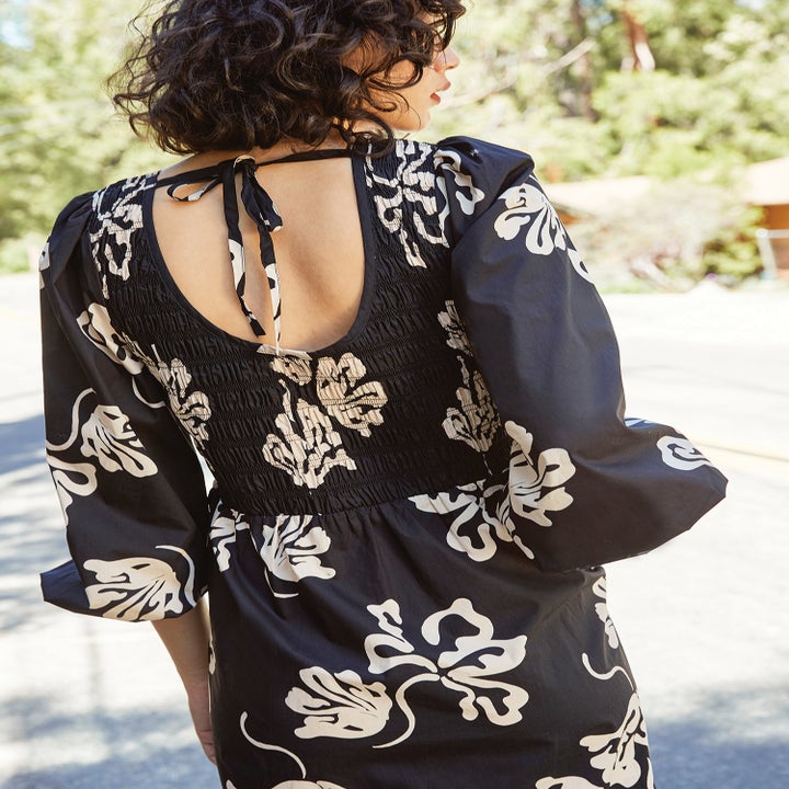 a model showing the back of the dress in black with flower print in white