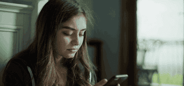 Young woman texts on phone frantically and then puts it to the side