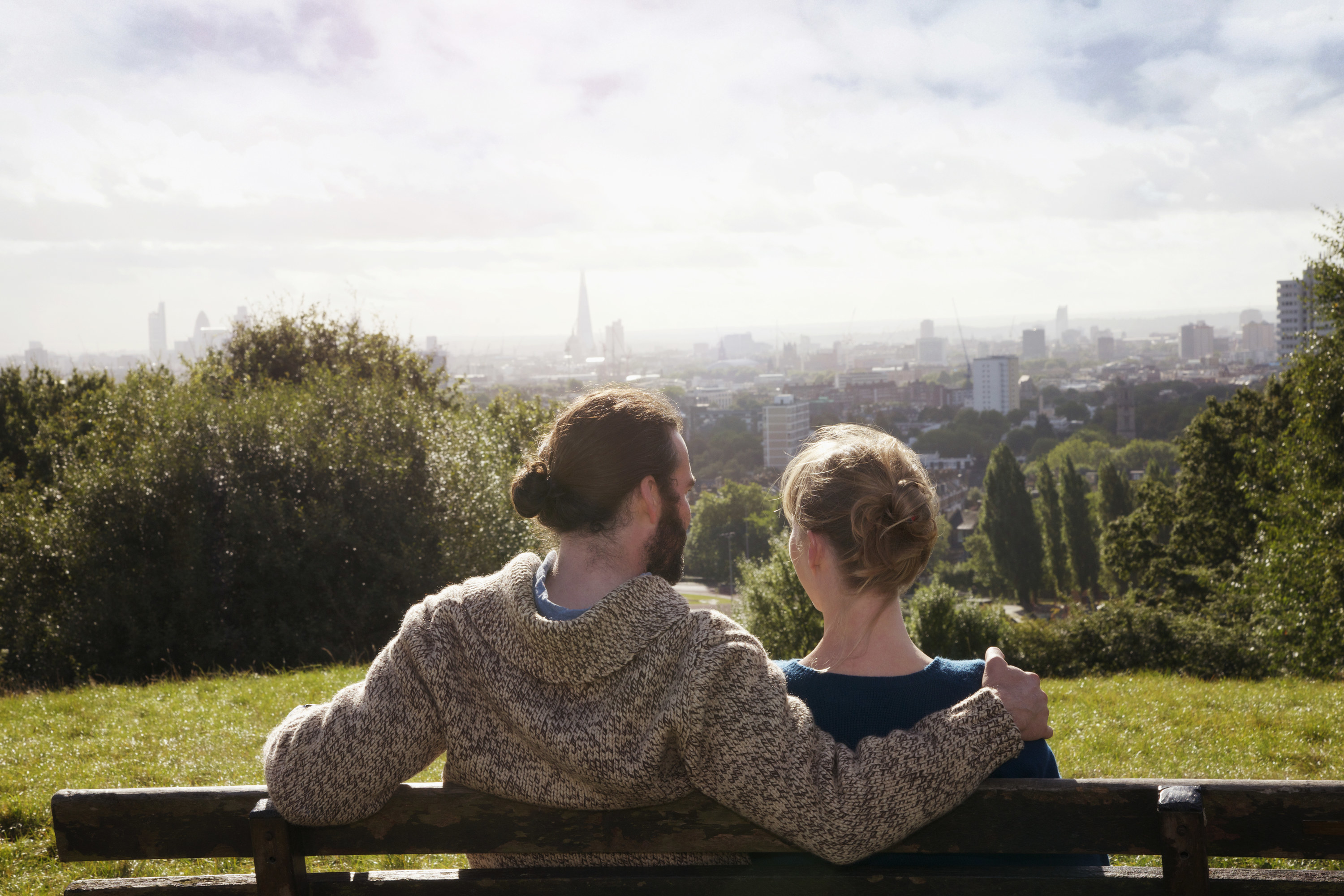 A couple sits on a bench with a view overlooking the city