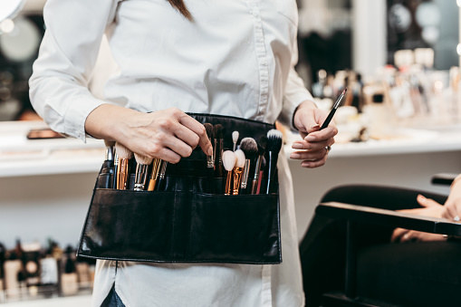 A makeup artist with a belt containing their tools