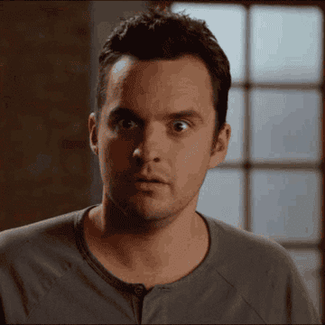 Jake Johnson in a black henley and eyes widened