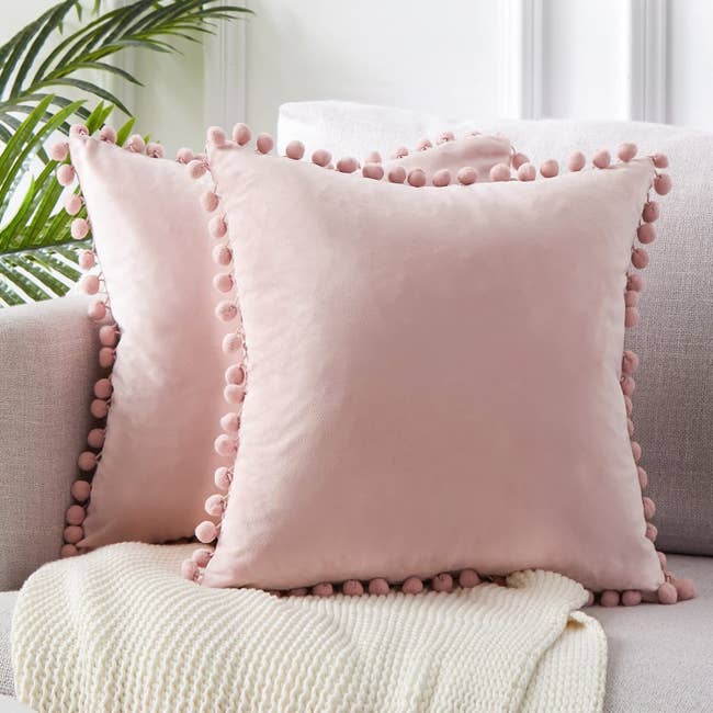 the square velvet pillows in baby pink on a couch