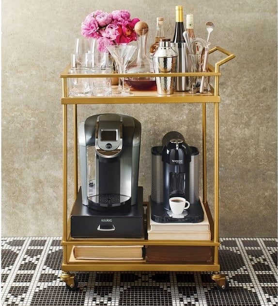 the bar cart with coffee makers and glassware and bottles on it