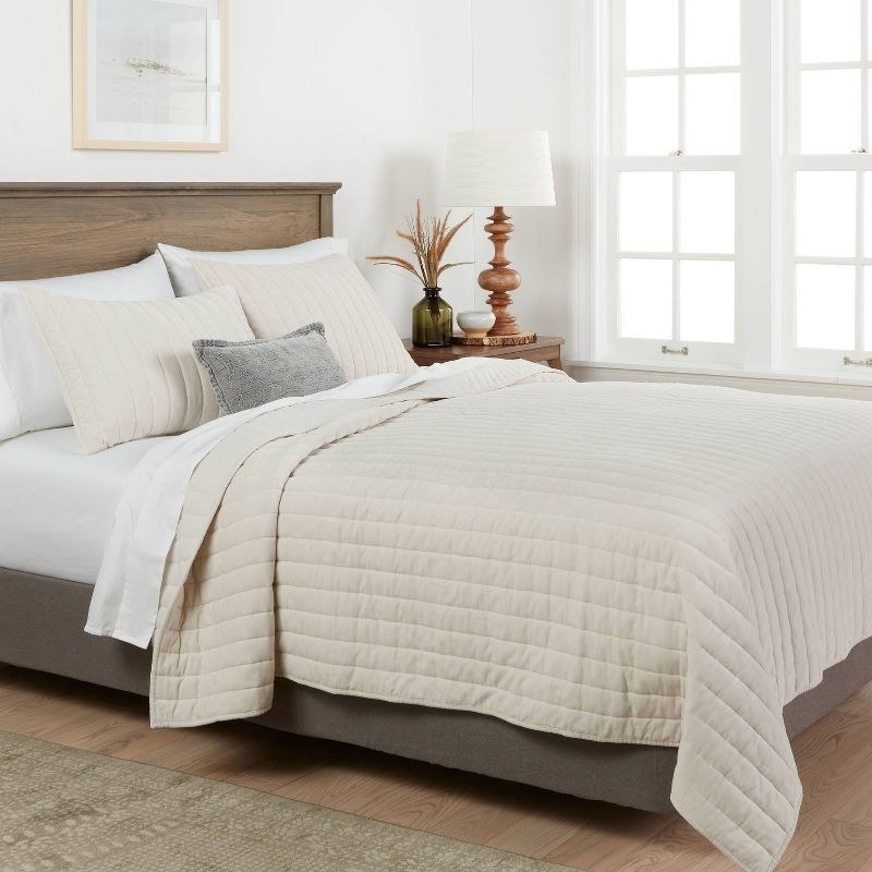 the cream colored quilt on a bed