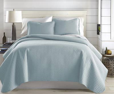 a light blue quilt set on a bed