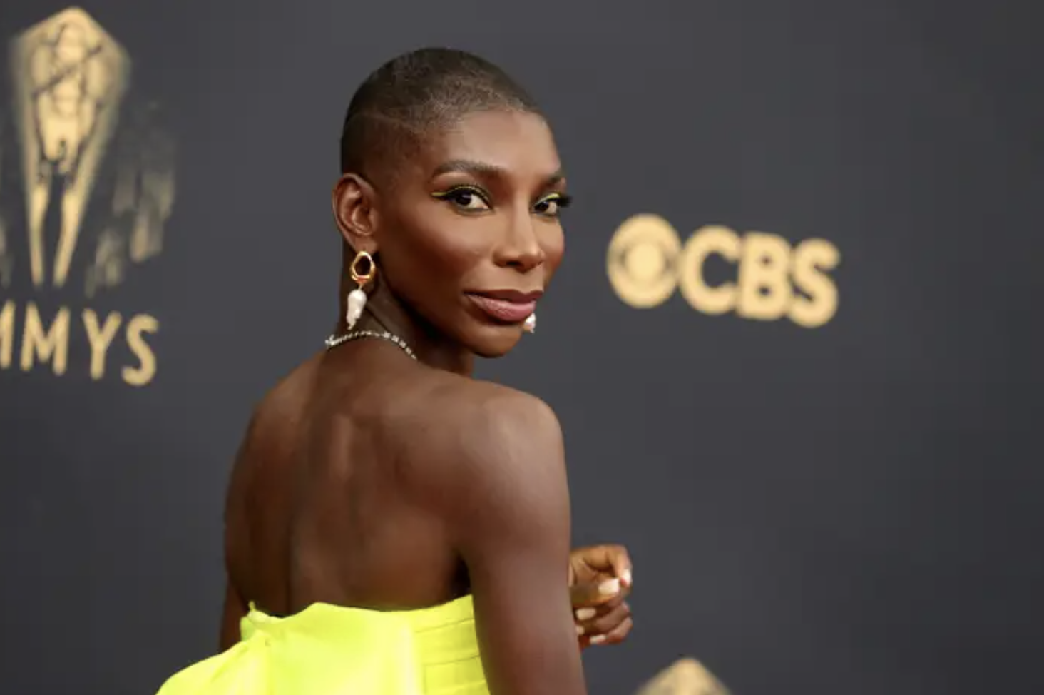 Michaela Coel looking back at the camera in a yellow dress, looking great