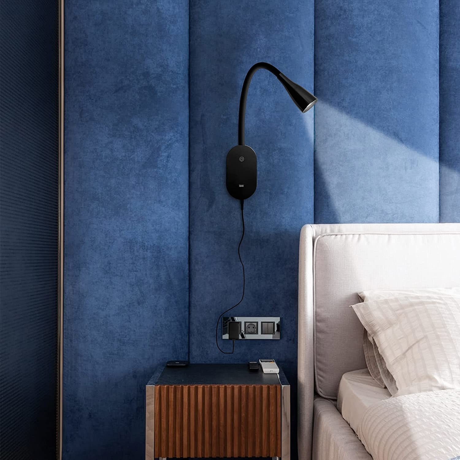 the wall lamp above a side table projecting on a bed