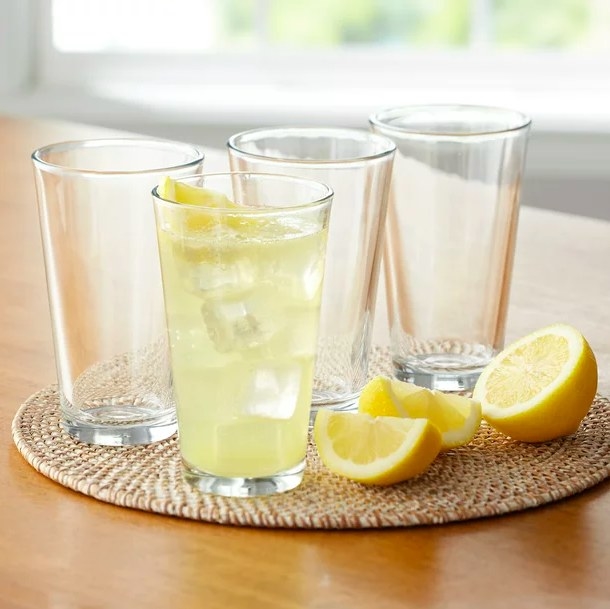 Glasses on a round placemat with lemons and one filled with lemonade