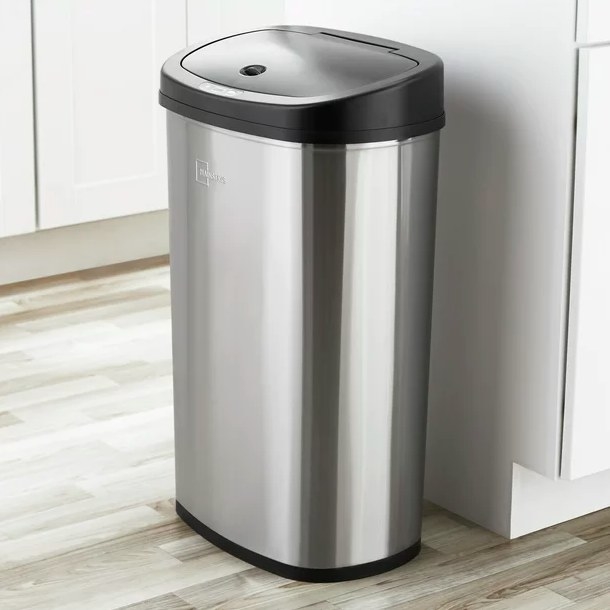 Stainless steel trash can next to white kitchen cabinet