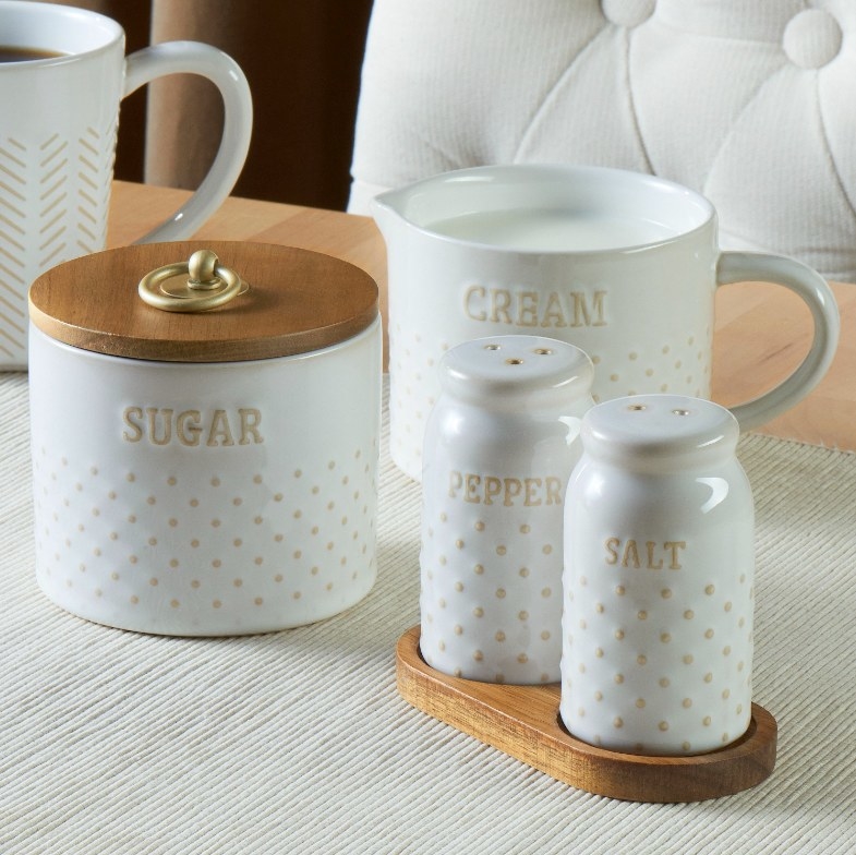 Salt and pepper shaker, sugar canister and creamer pitcher on a table