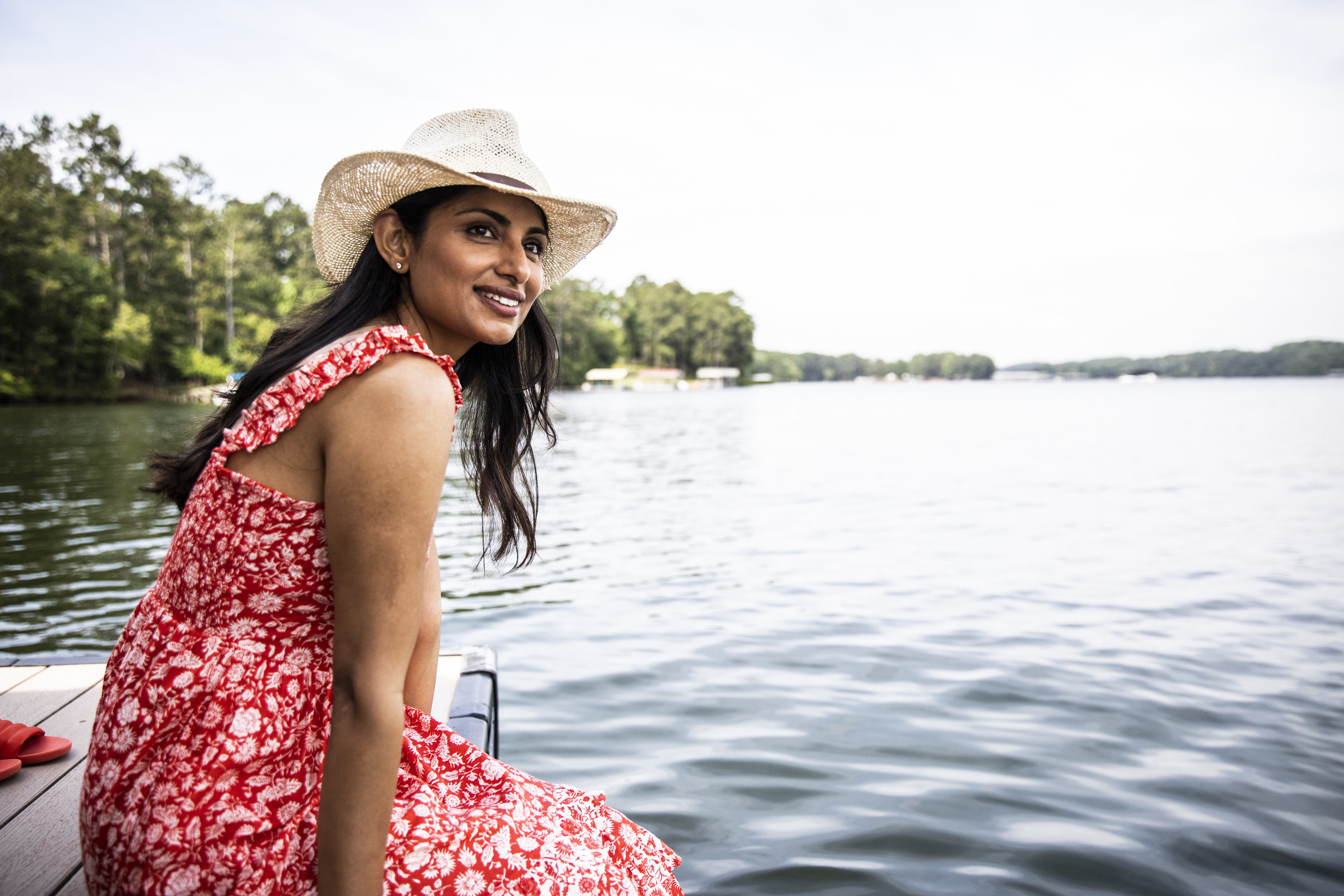 A woman sits on a dock by a lake