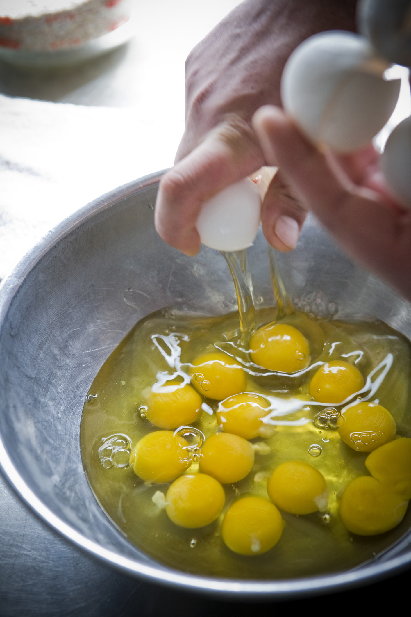Hands cracking eggs into bowl.