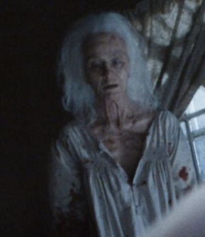 an elderly woman wearing a bloody nightgown