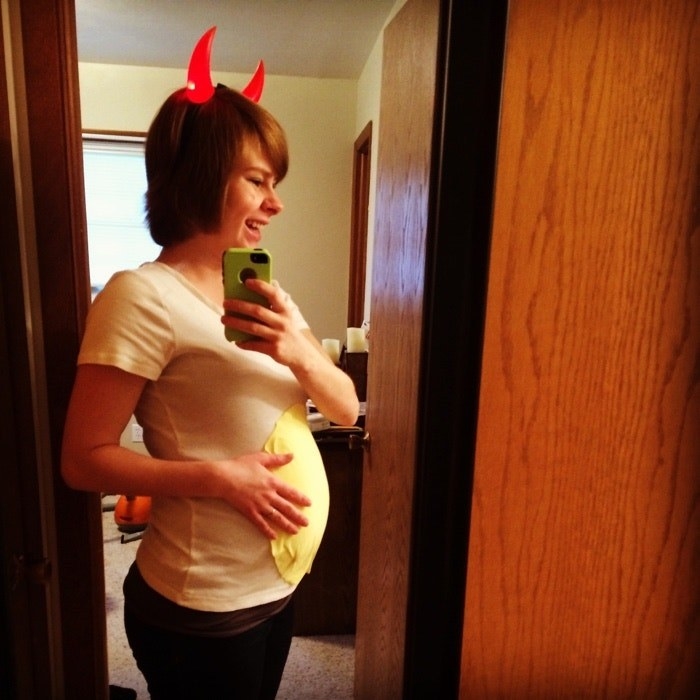 a woman wearing devil horns and a yolk on her belly