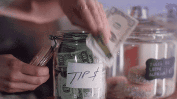 a hand stuffing cash into a jar