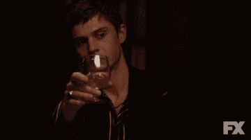 Evan Peters drinking a glass of wine in American Horror Story