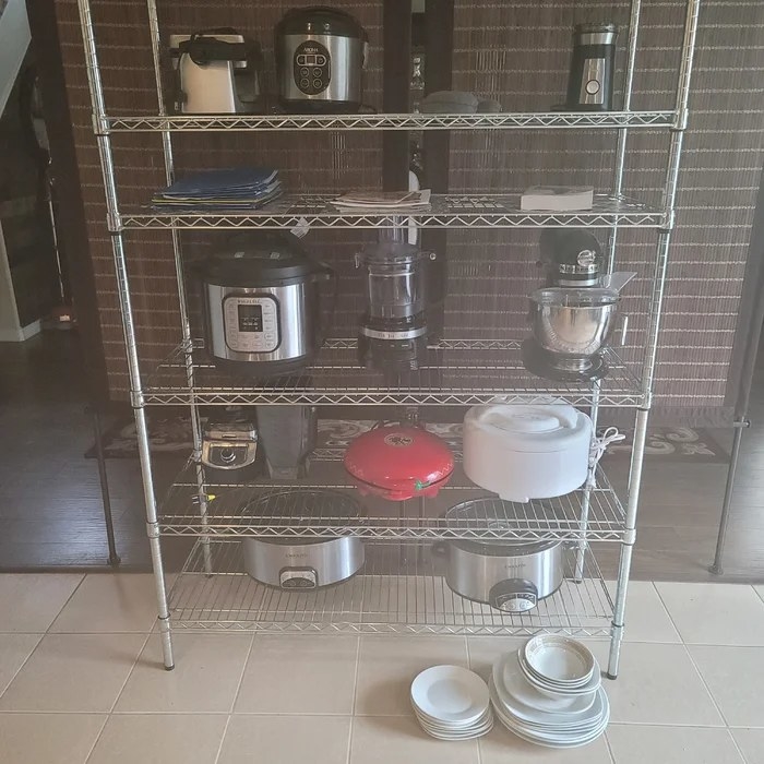 A six-shelve wire rack with pots stacked ontop of it.