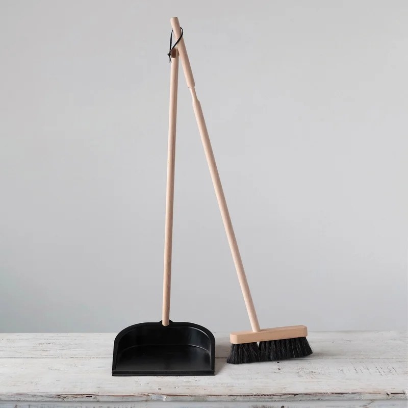 A push broom and metal dustpan both with wooden handles