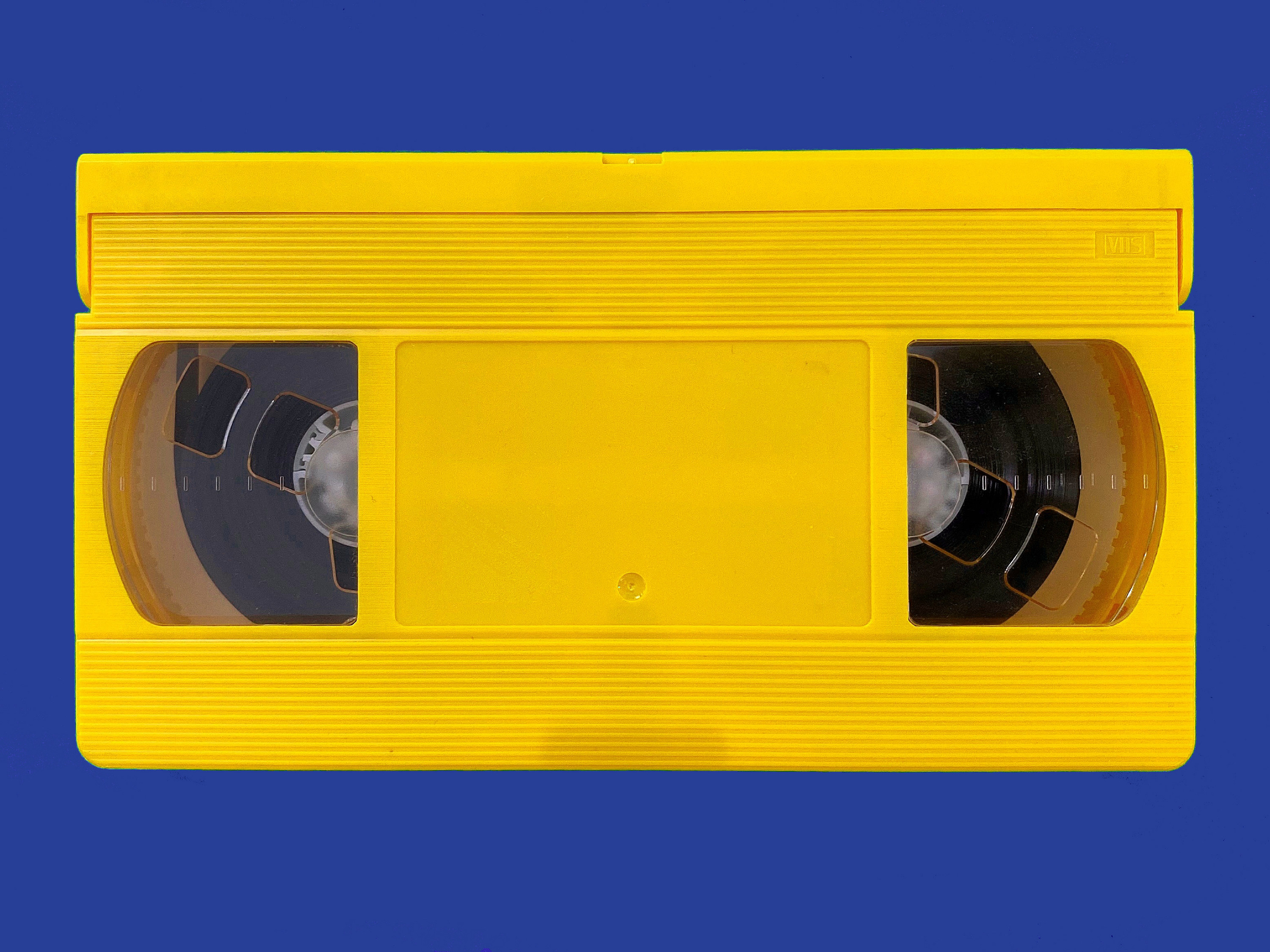 Yellow VHS cassette on blue table