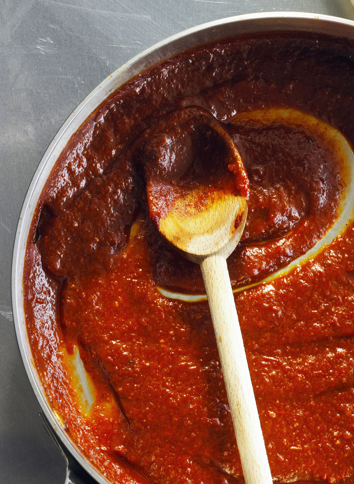 A spoon in a pan of tomato sauce