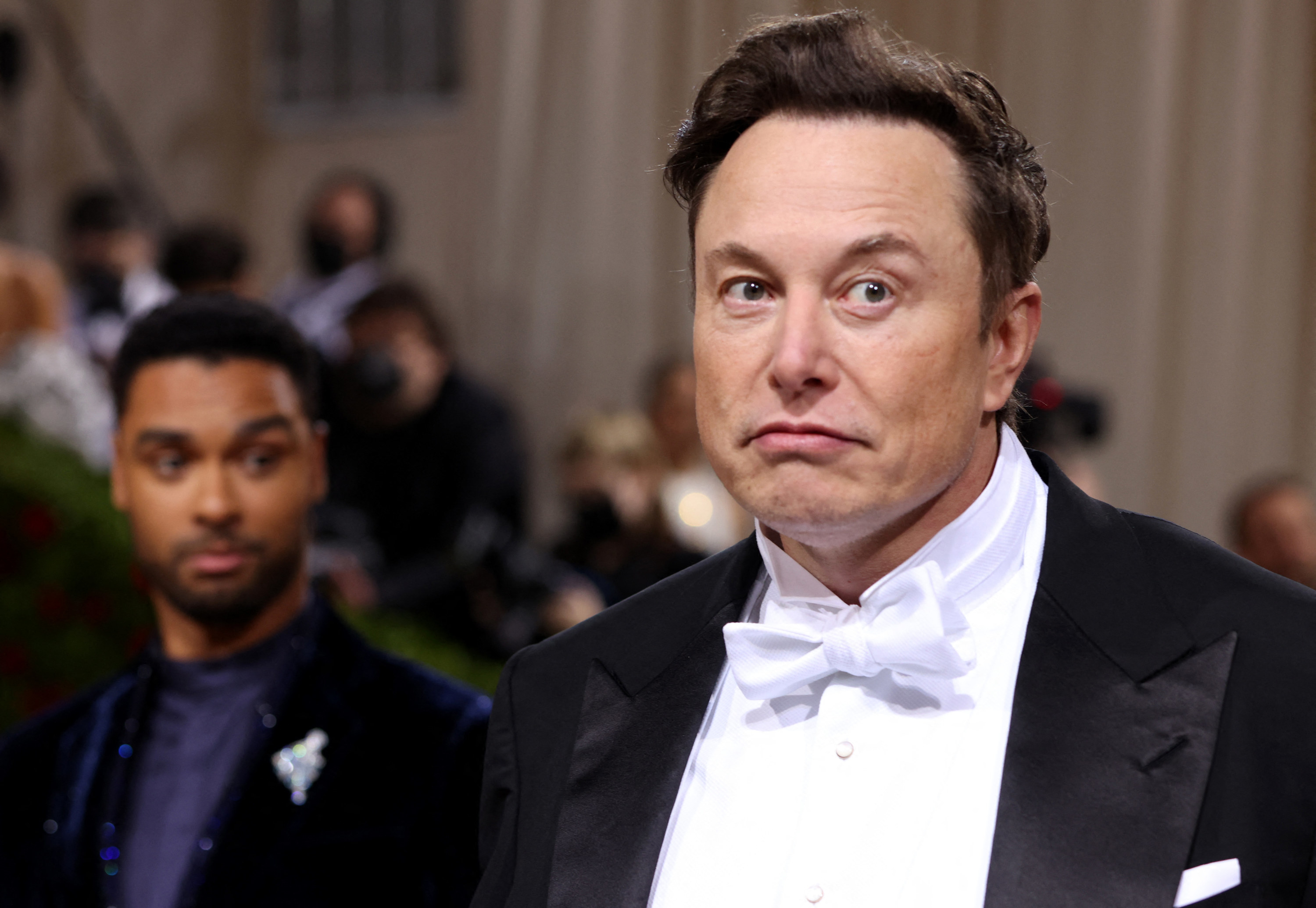 Elon Musk frowning while wearing a tuxedo