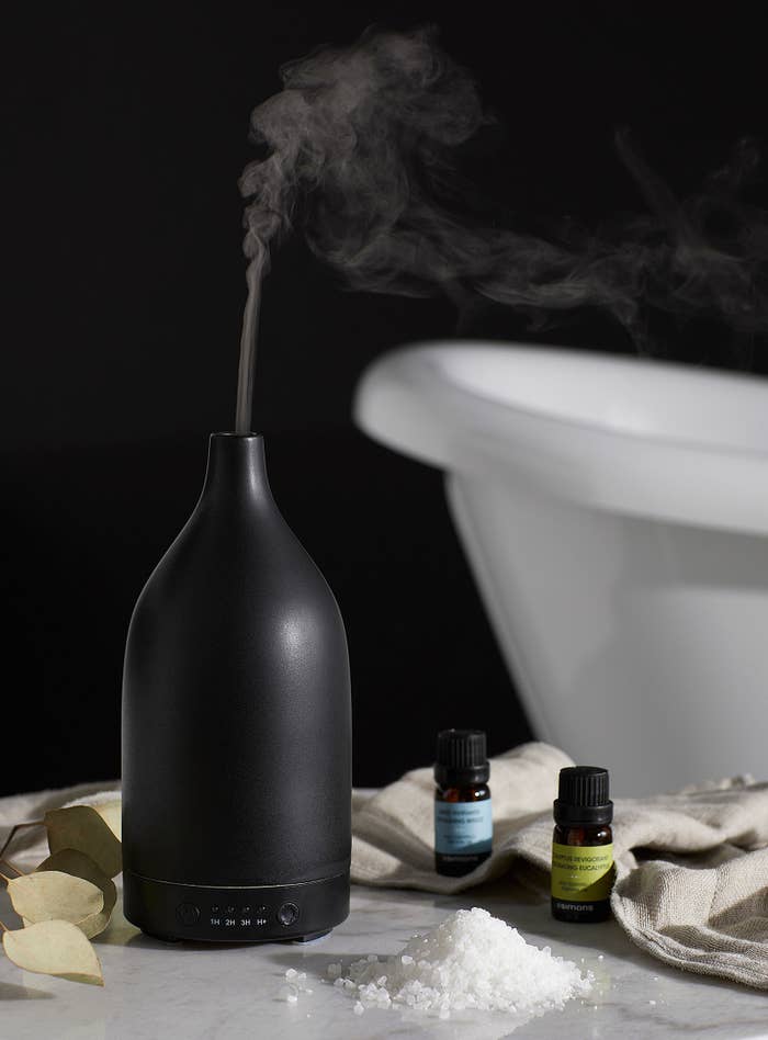a sleek diffuser next to salts and essential oils