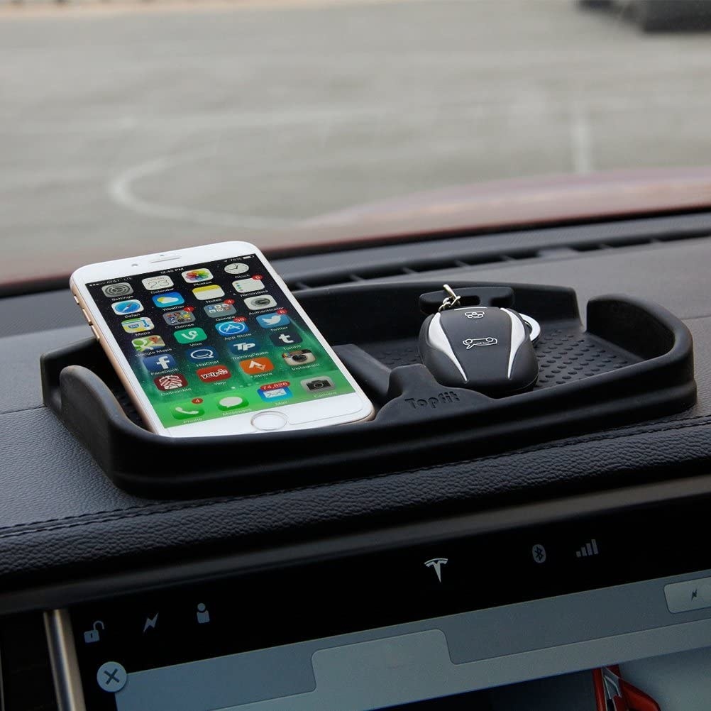 the dash tray on a dashboard with a phone and key fob in it