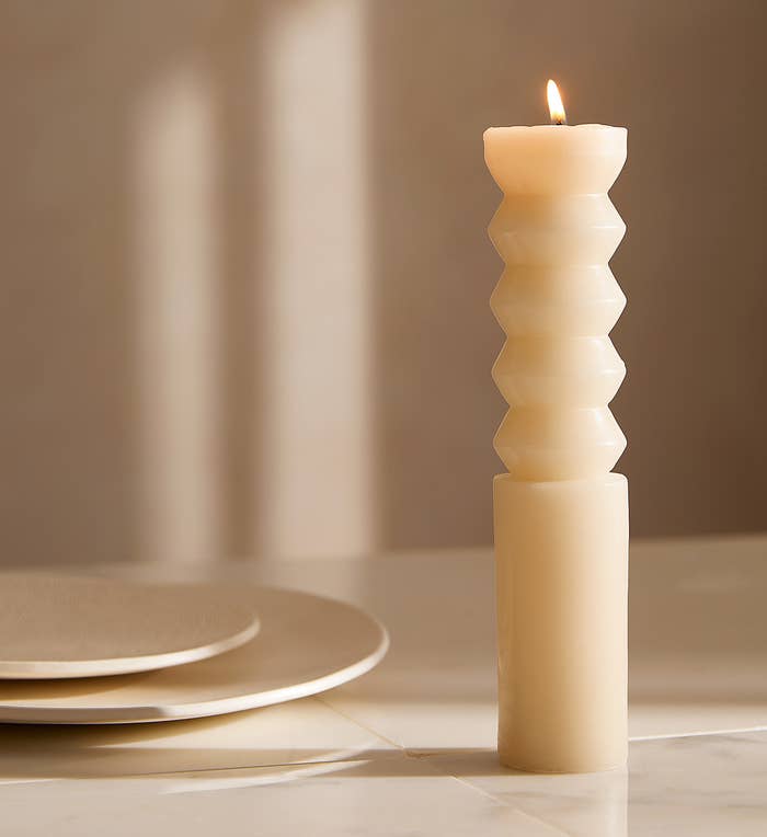 a pillar candle on a table next to two plates