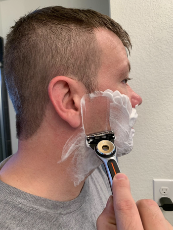 reviewer shaving with heated razor on face