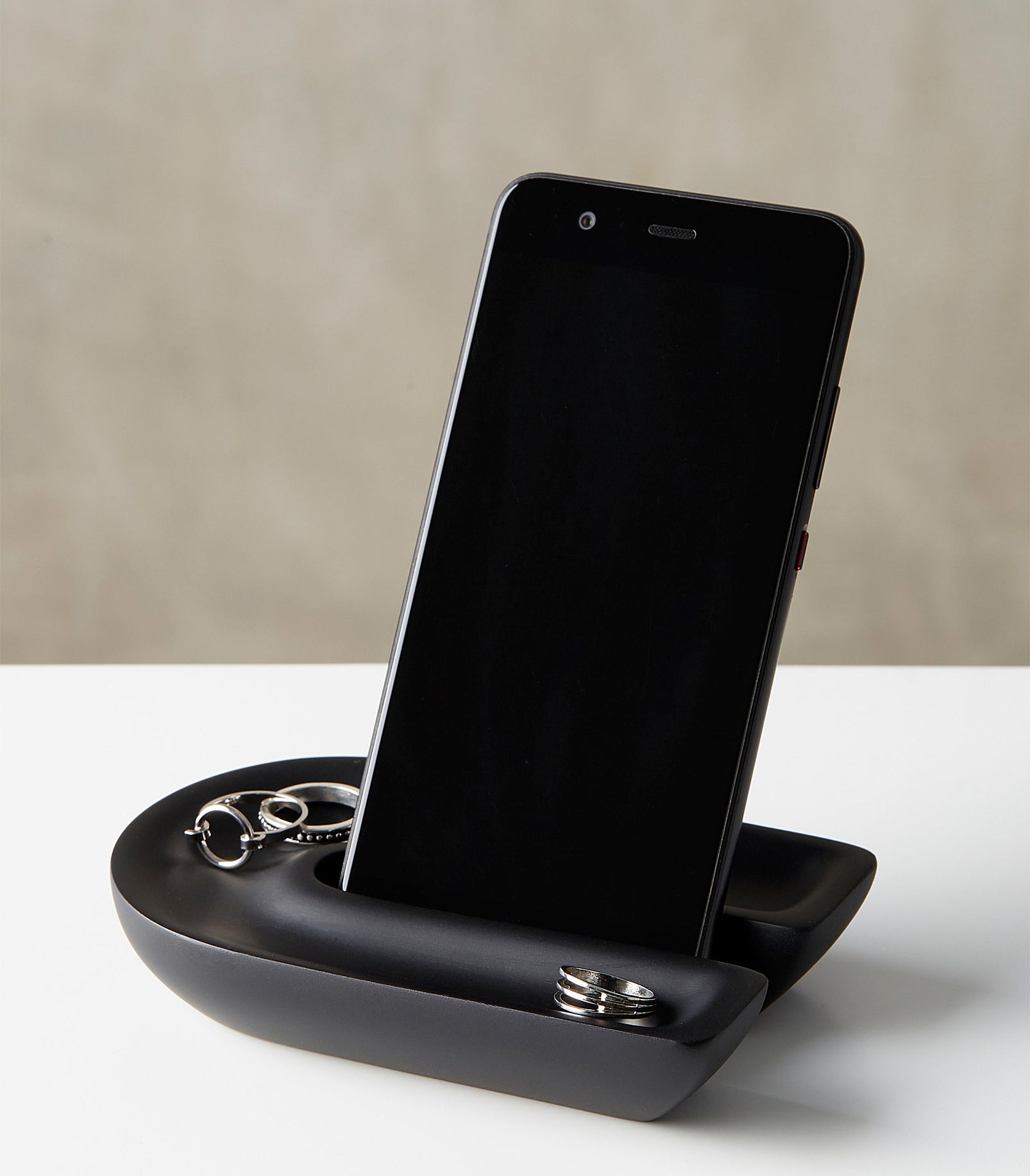 a phone in a u-shaped phone holder that is also holding rings