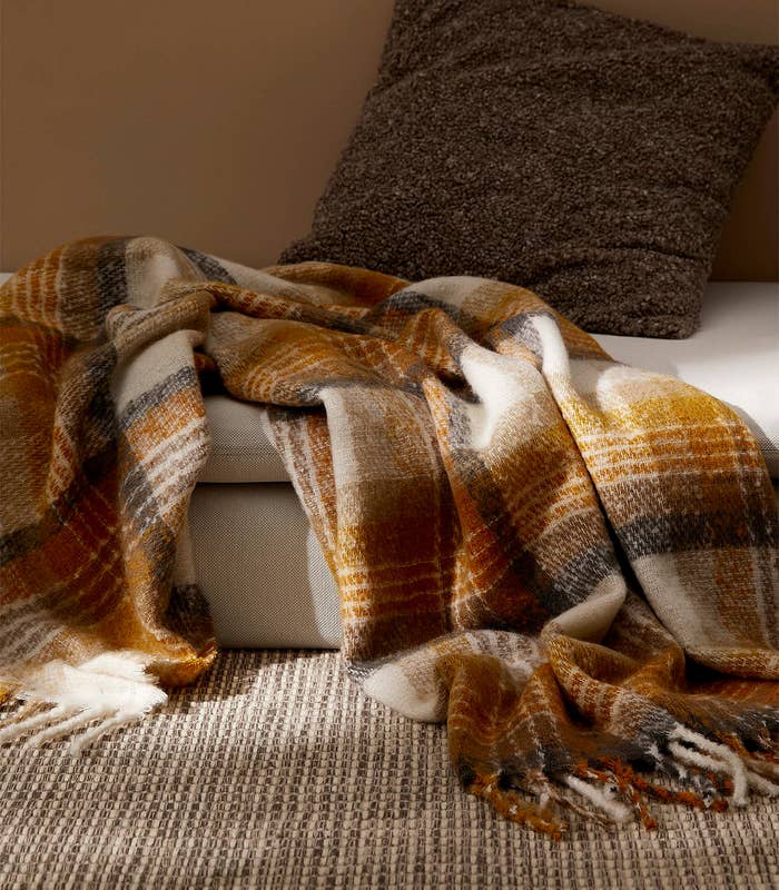 a cozy throw blanket on a low couch next to a pillow