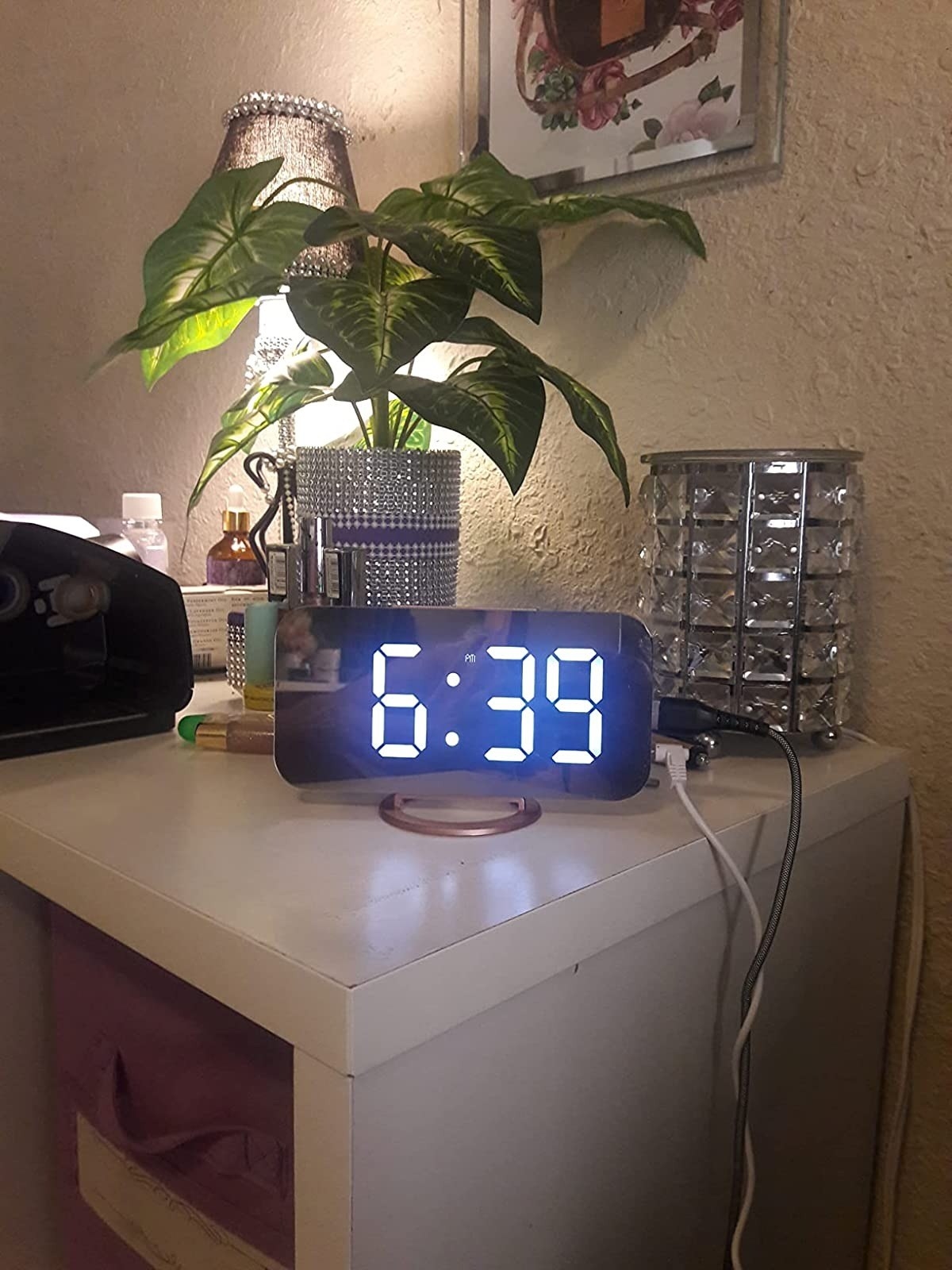 lit-up mirrored digital alarm clock on white nightstand