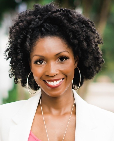 A photo of Dr. Rheeda Walker, a smiling, friendly Black woman with tight curls pulled away from her face. She has big silver hoops and wears a white jacket