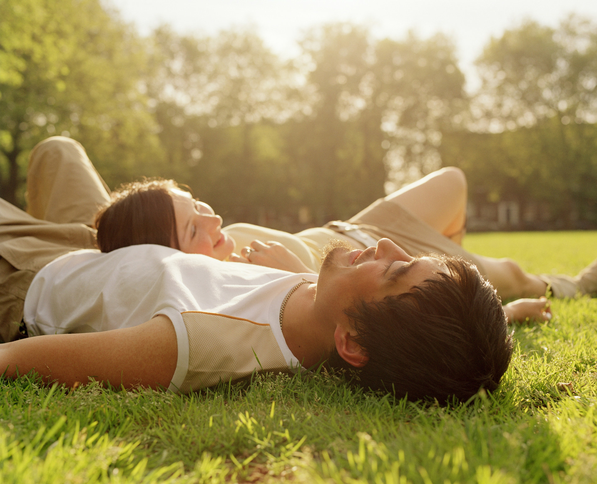 A couple laying in the grass and smiling