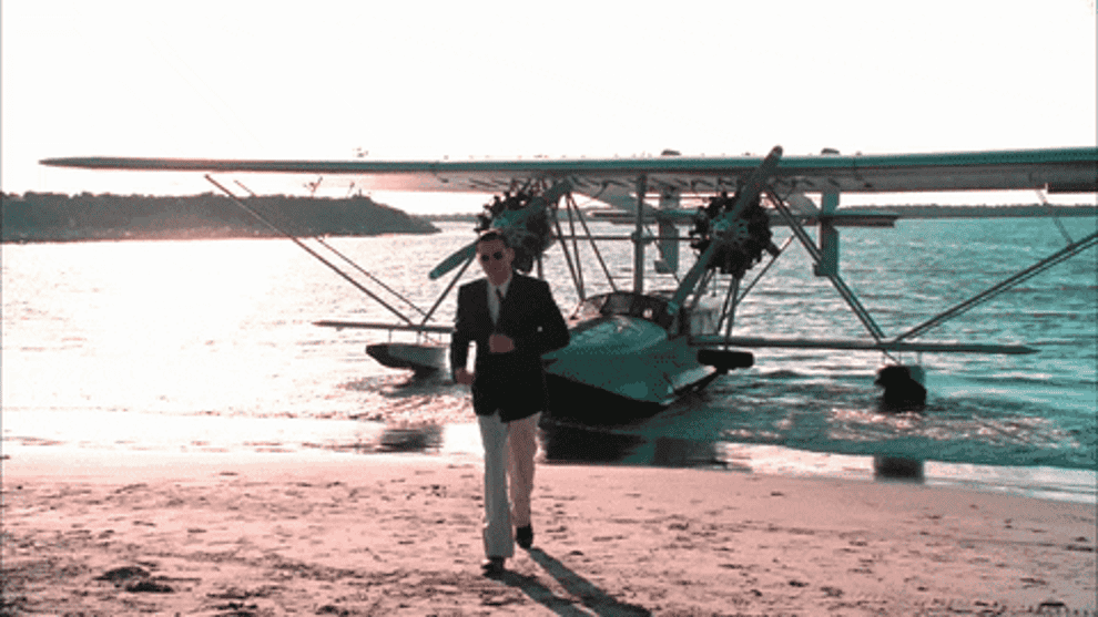 Leonardo DeCaprio walks on a beach away from a seaplane