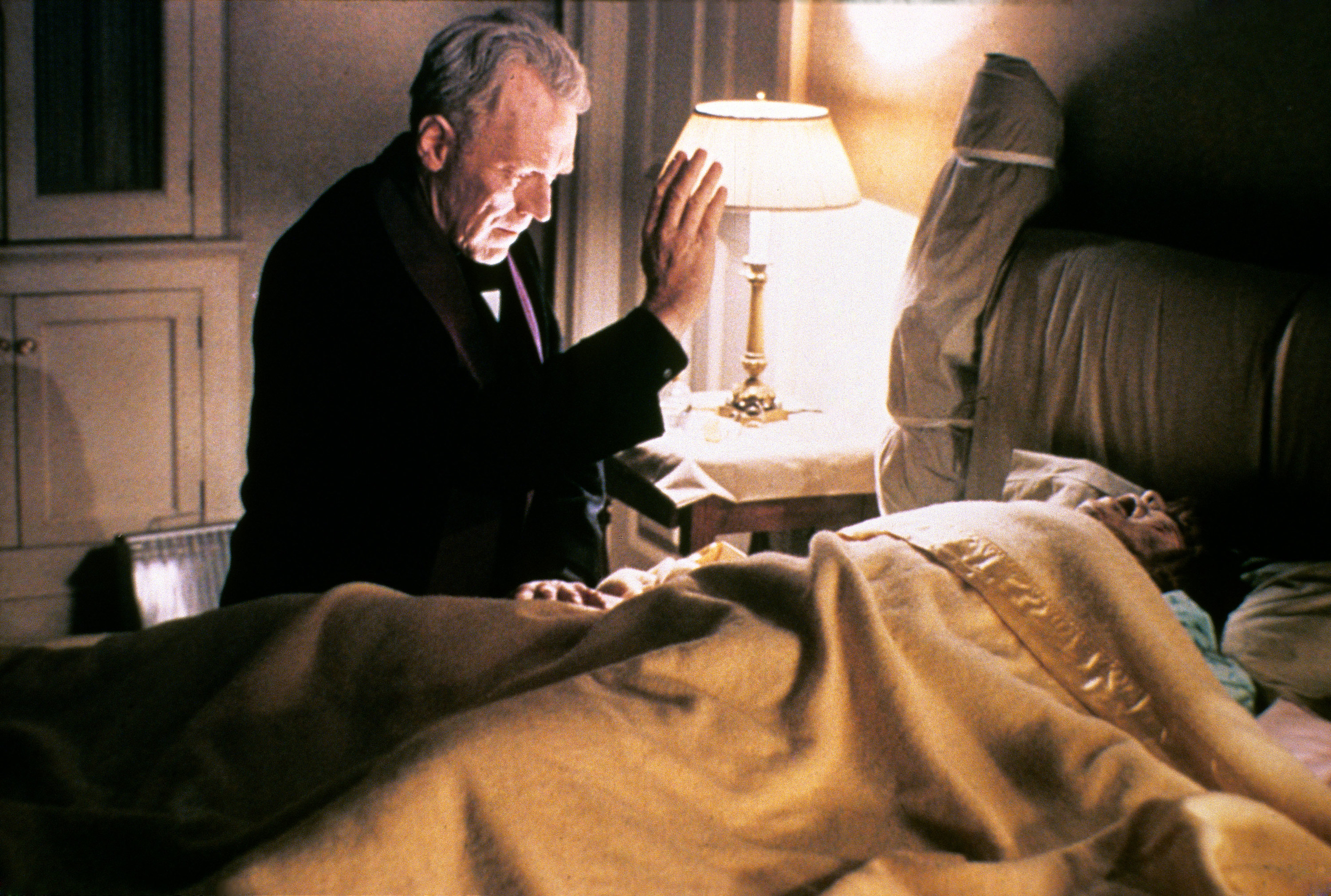 priest praying over a person in bed