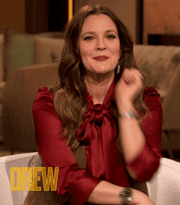 A GIF of Drew Barrymore leaning in and looking interested