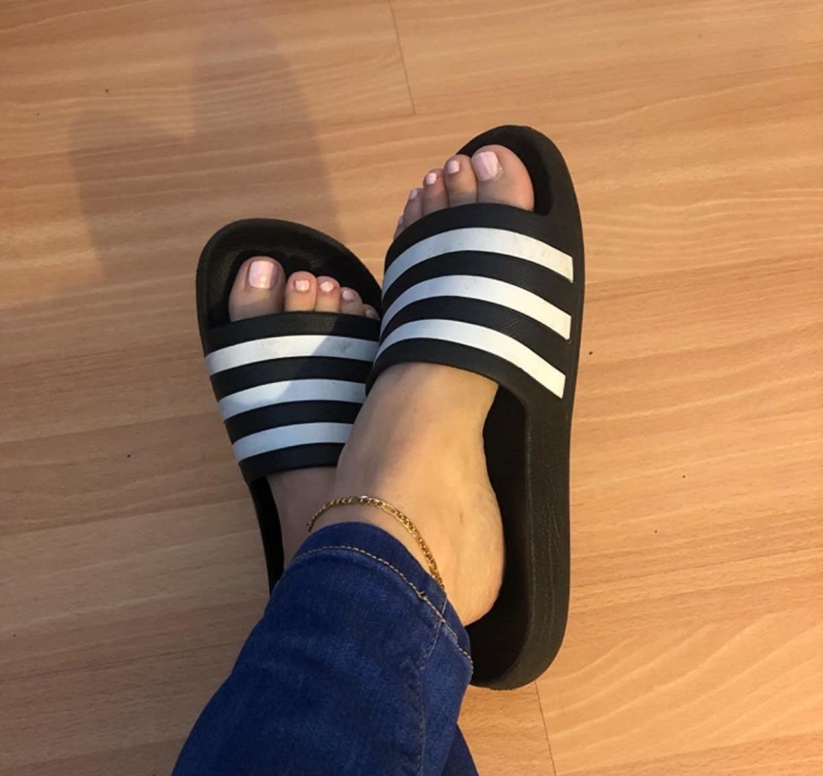 Reviewer black adidas slides with white stripes on the front foot panel