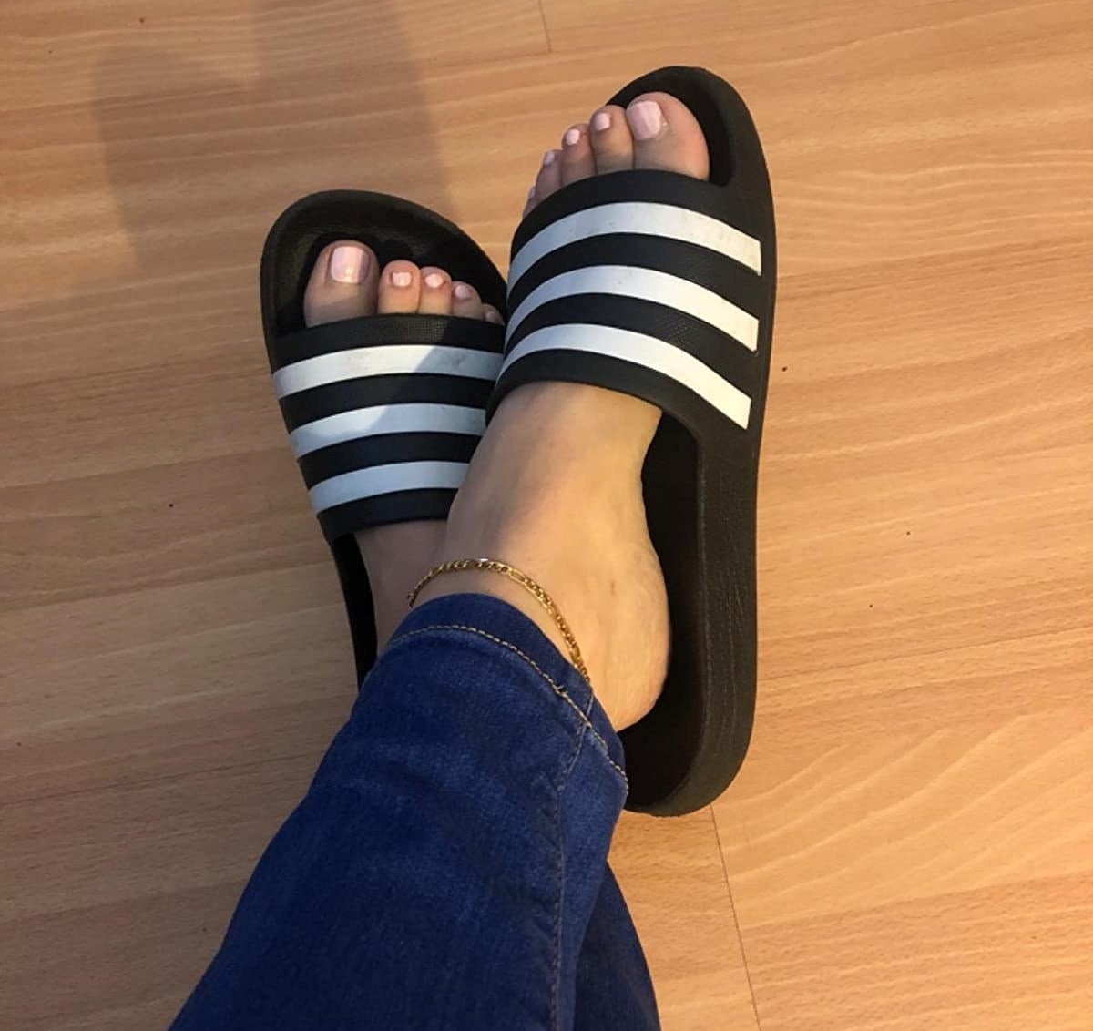 Reviewer black adidas slides with white stripes on the front foot panel