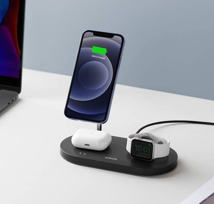a pair of airpods, an apple watch, and an iphone charging on the anker station