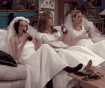 monica rachel and phoebe from friends in weddings dresses sitting on couch drinking beer