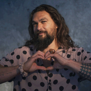 Jason Mamoa smiling making a heart with his hands and then putting them to his cheeks
