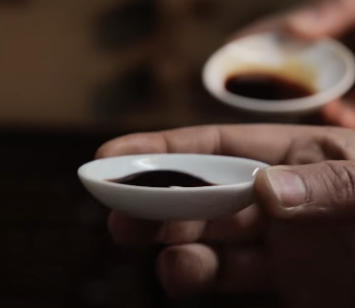 holding small ramekins of thick, syrupy soy sauce