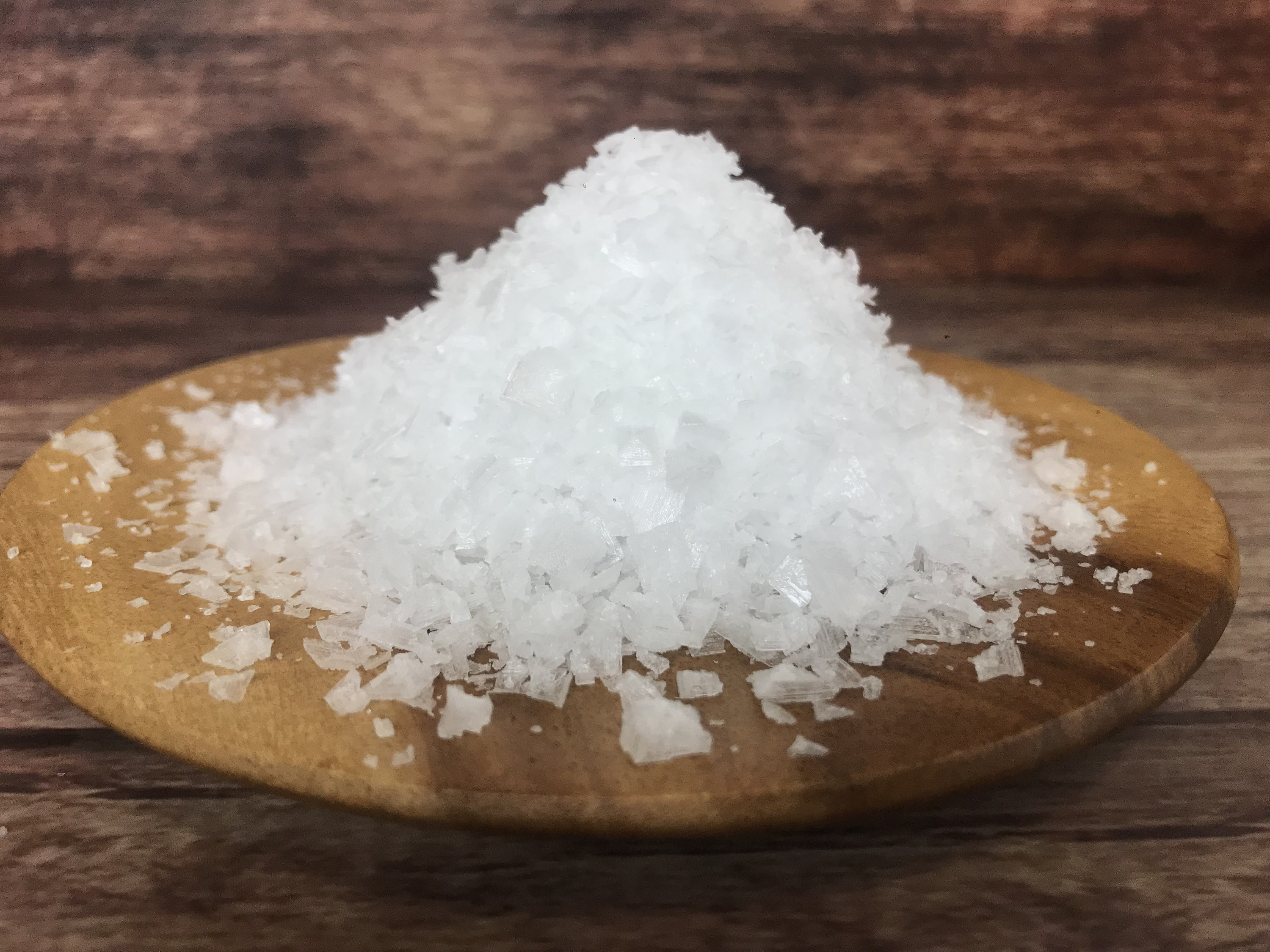 flaky salt piled high on a wooden board