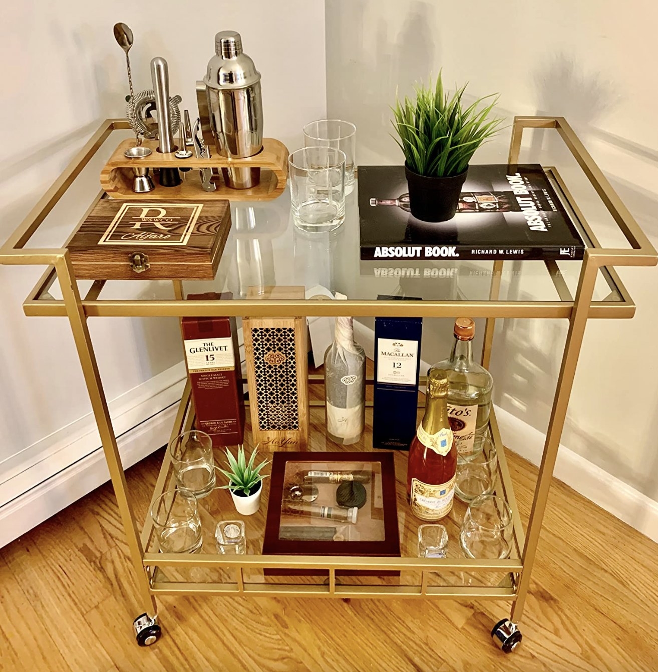 gold bar cart with different barware and drinks on the shelves