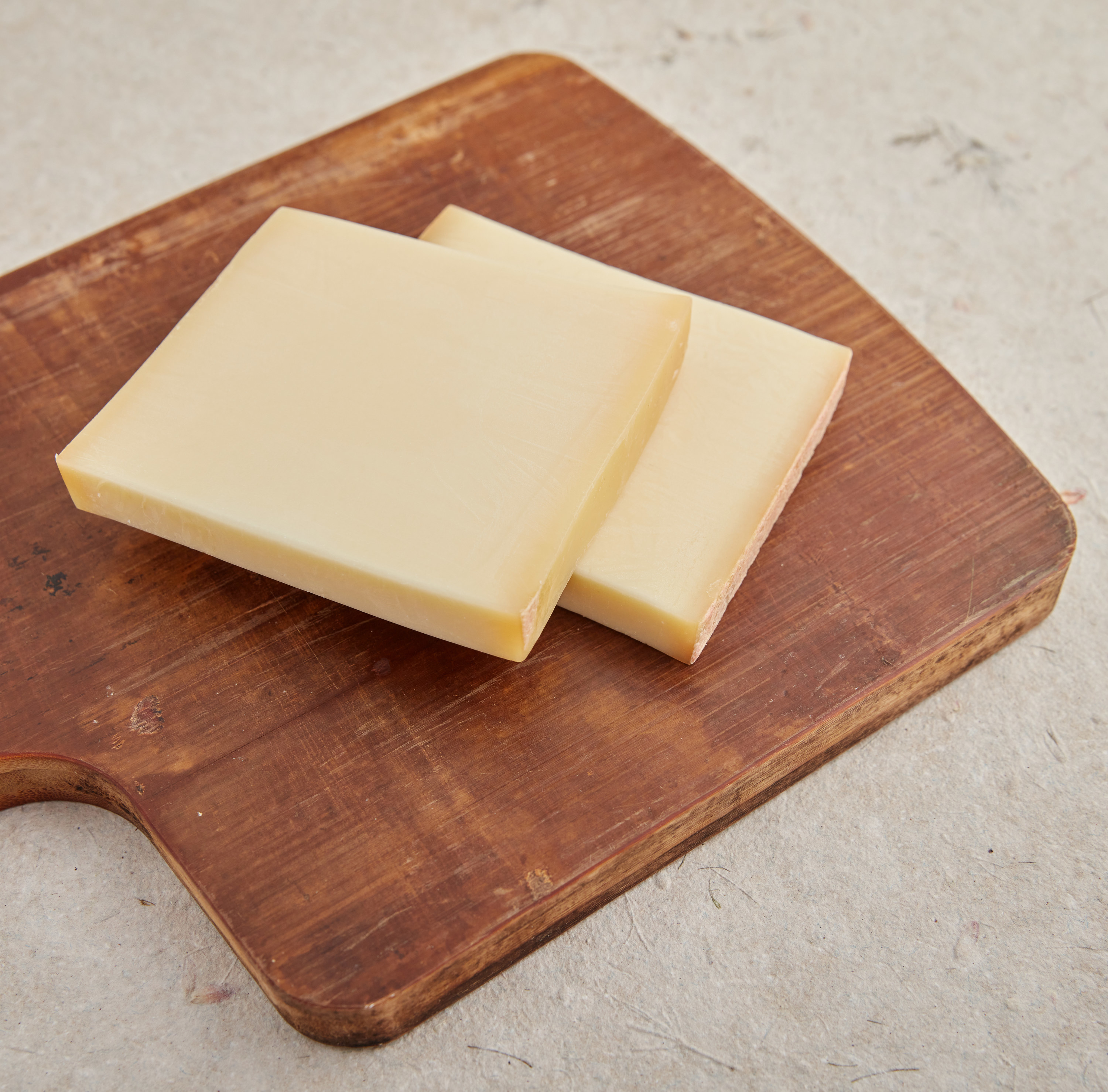 two pieces of gruyere cheese on cutting board