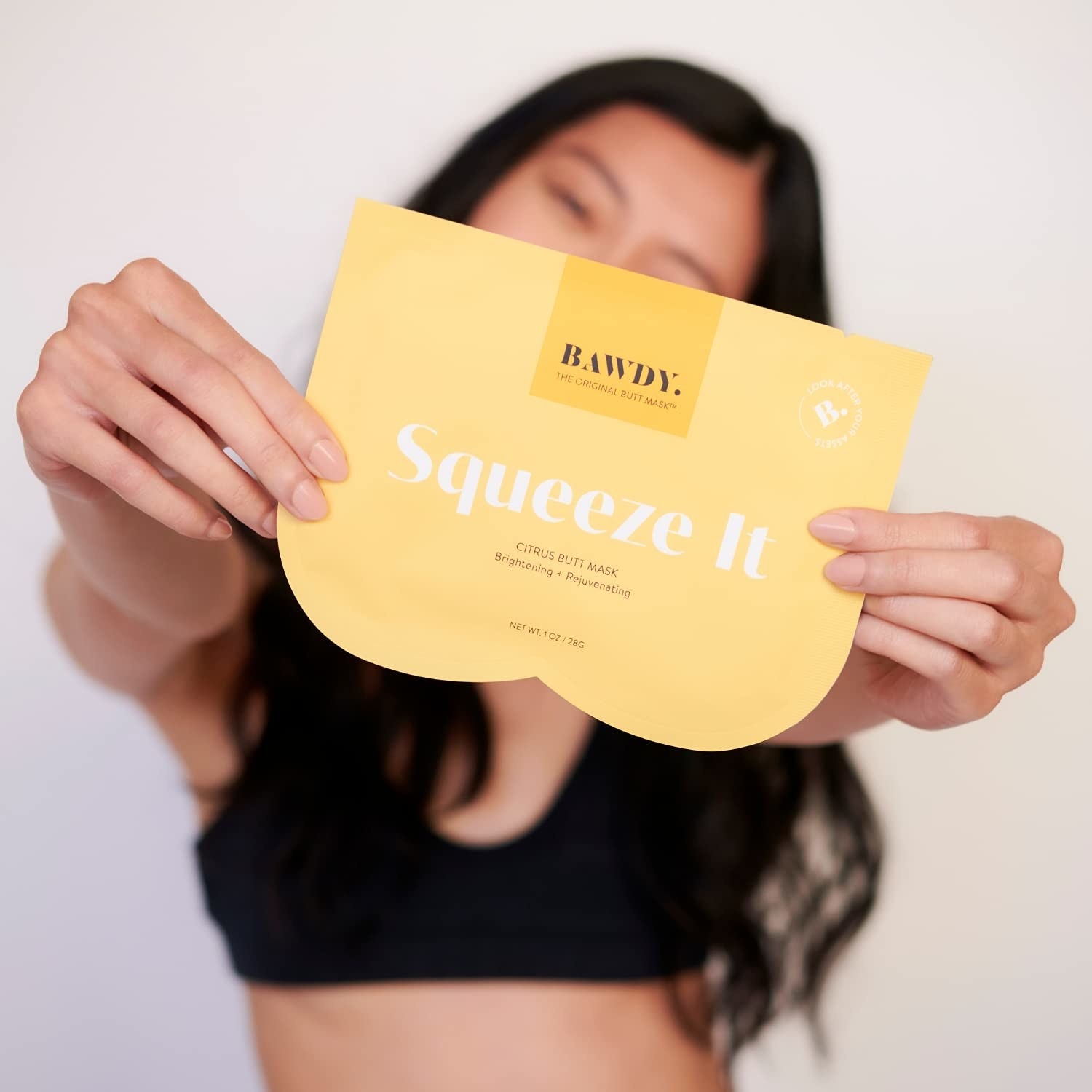 a model holding up the butt mask in yellow packaging that says &quot;squeeze it&quot;