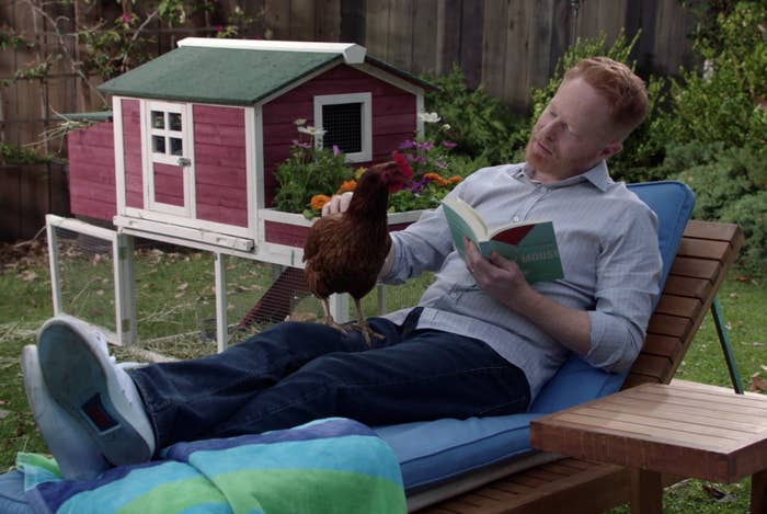 Mitch laying on a lounge chair in his backyard with the chicken on his lap