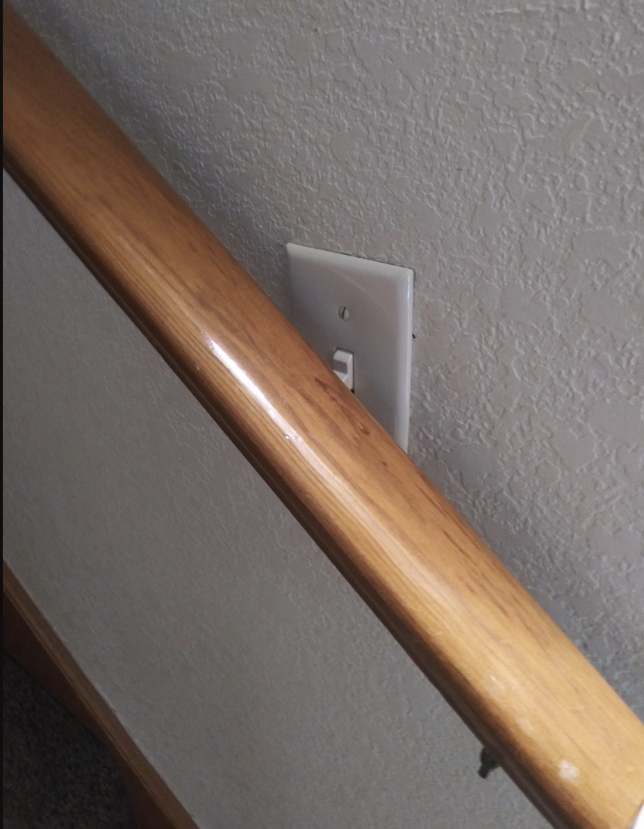 A light switch blocked by a railing